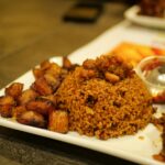 Close-up of West African Jollof rice with fried plantains, ideal for food lovers.